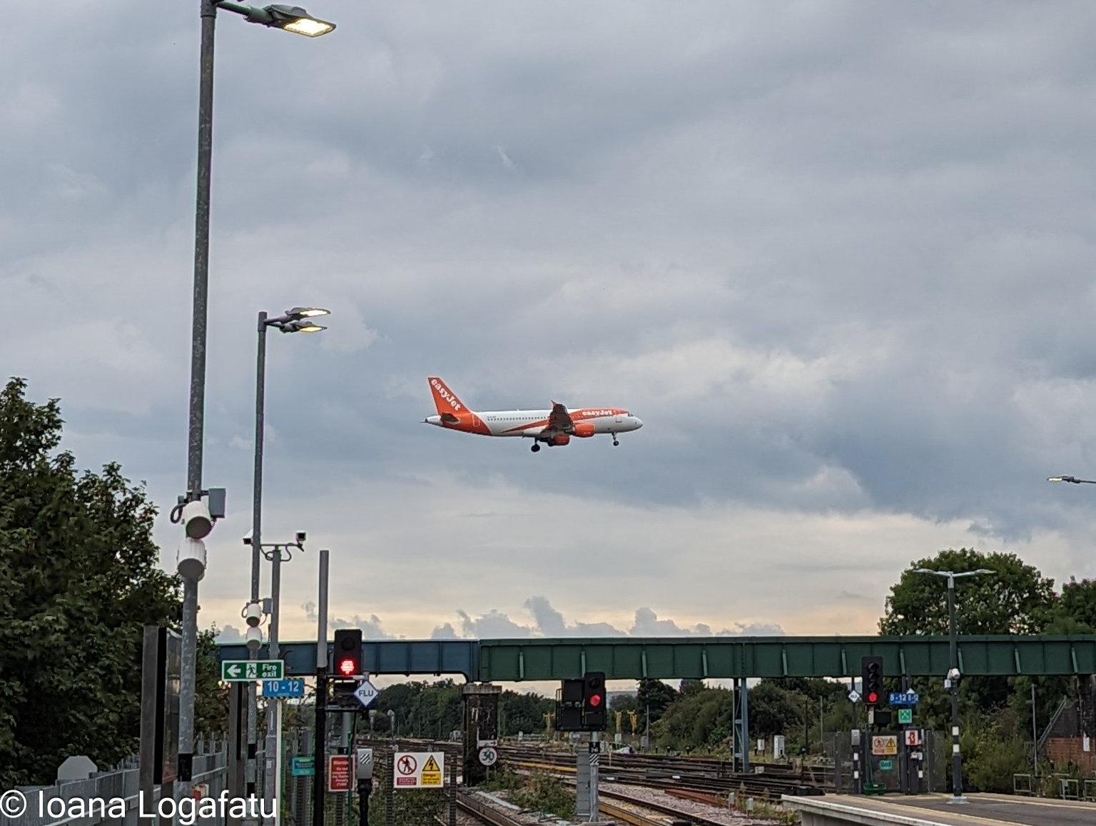 Plane lands by train tracks in cloudy sky